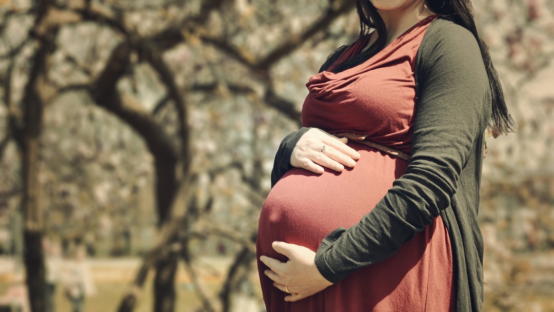 Pregnant woman holds her belly in autumn colors outdoors