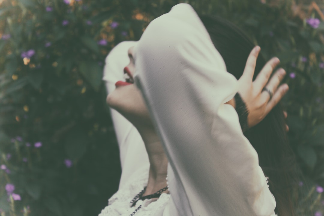 A woman dressed in white is tying her hair.