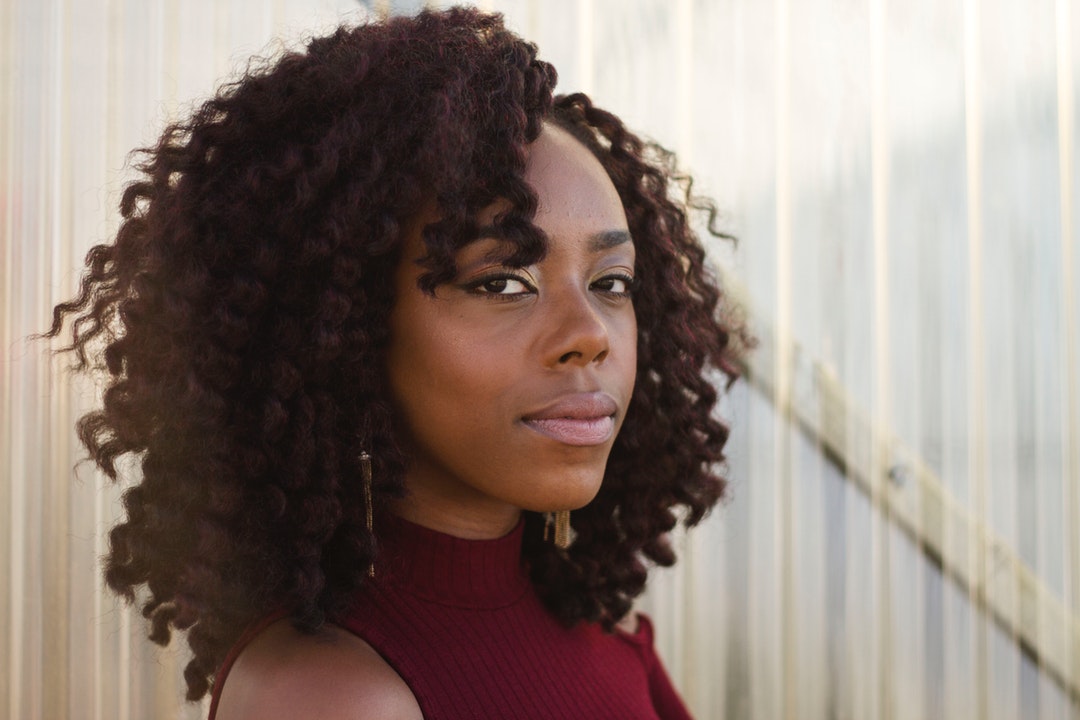 Woman with curly hair looks confidently into camera
