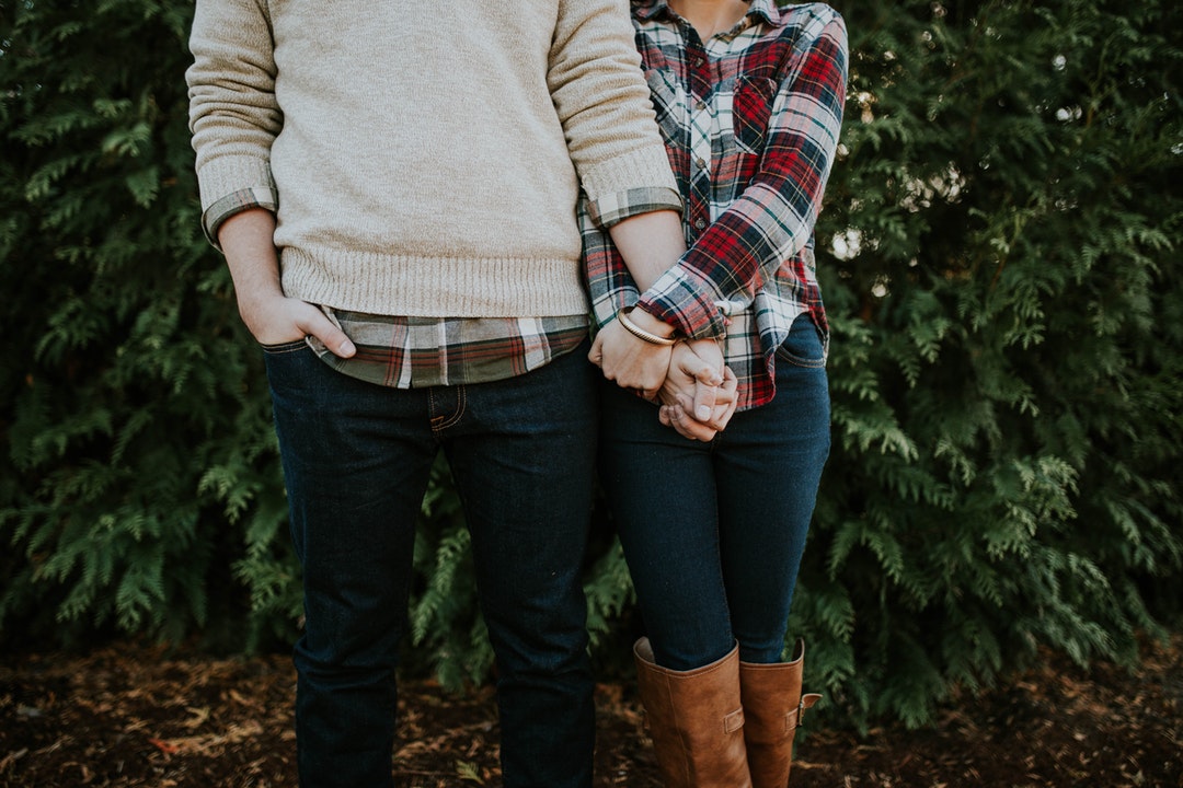 Couple in plaid, jeans, and sweater holding hands at Botanical Garden of the Ozarks