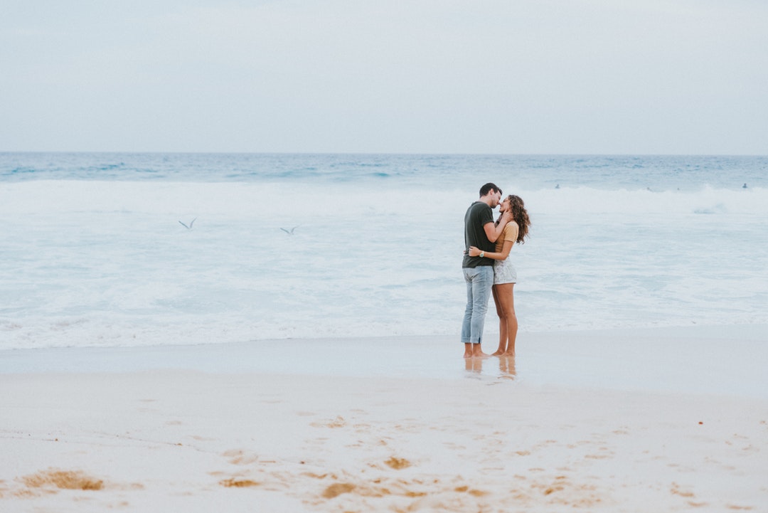 On Bronte Beach, sea birds skim the surface while a man and a woman share tender moment