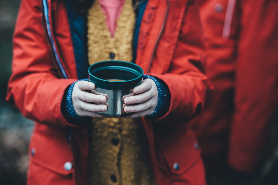 Child wearing raincoat, standing in the cold and holding cup of soup in New Forest District