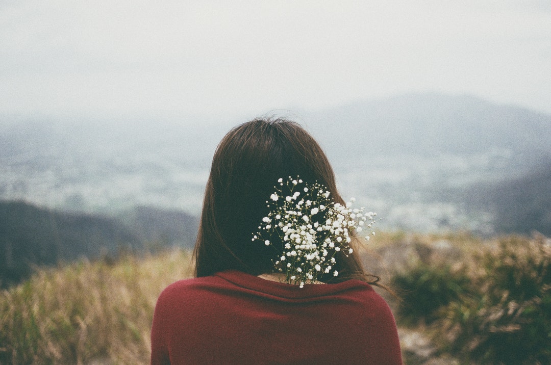 Woman with baby's breath flowers in her hair looking at a field