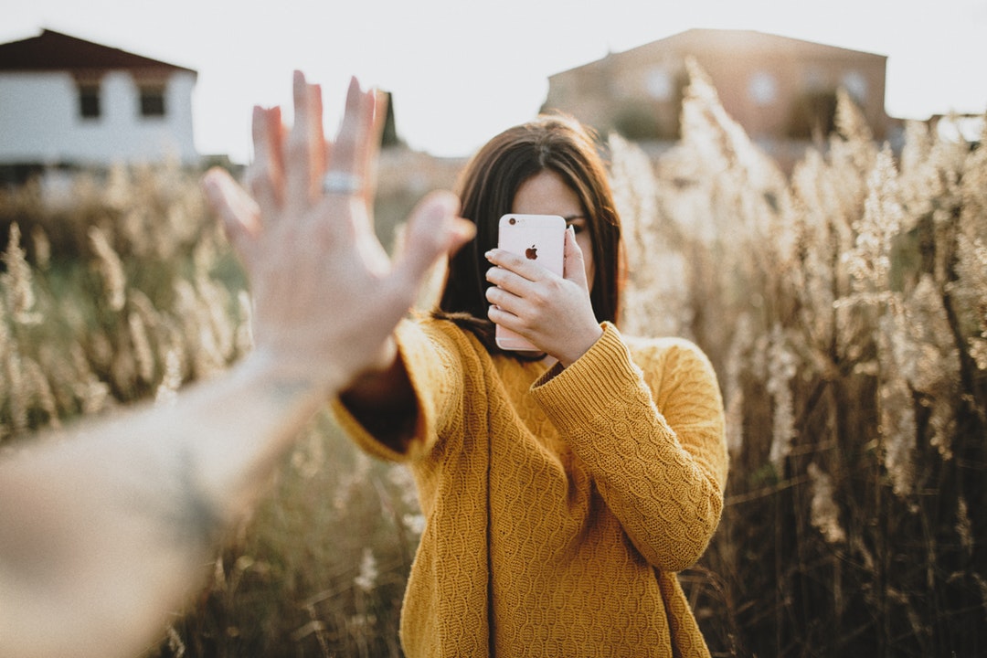 A woman is high-fived while holding her phone in a field.