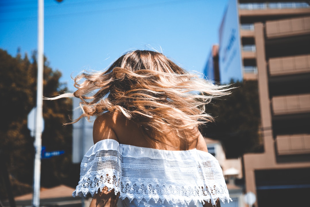 Walking behind a woman with windblown hair and an off-the-shoulder top