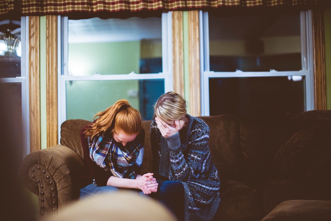 Two people in mourning or grieving on a couch in a living room