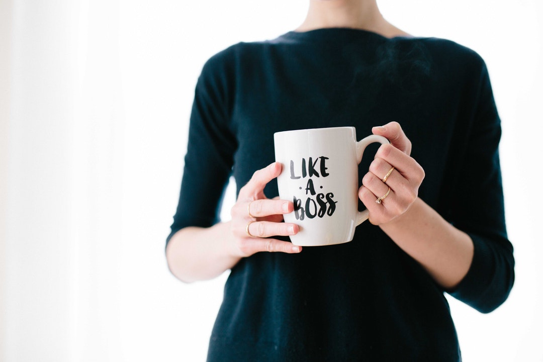 A woman holding a white mug with a “like a boss” print