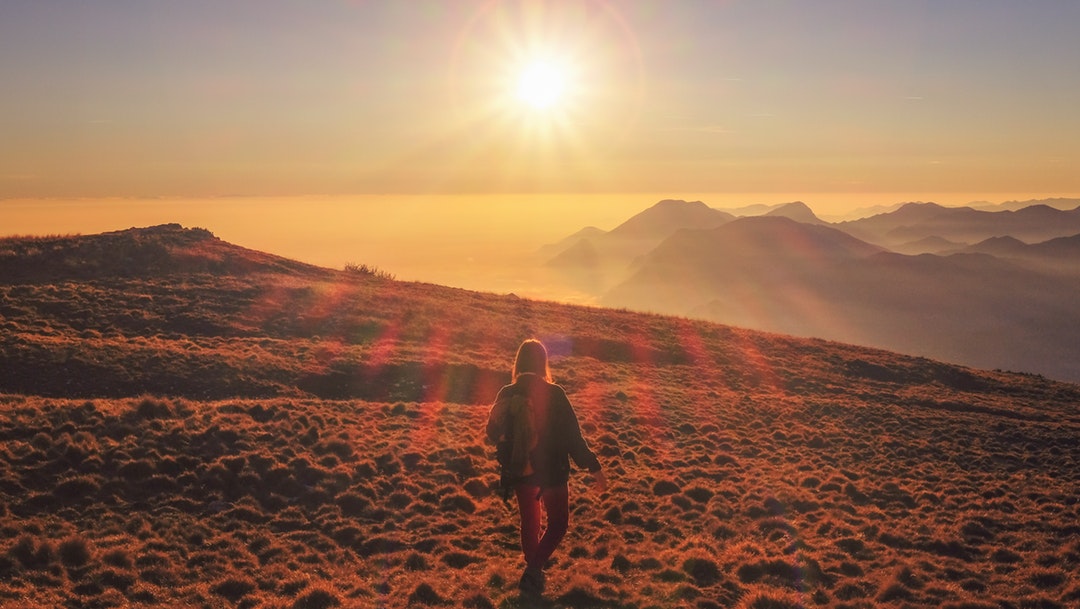 A woman walking on a mountain during sunrise or golden hour in Monte Altissimo di Nago
