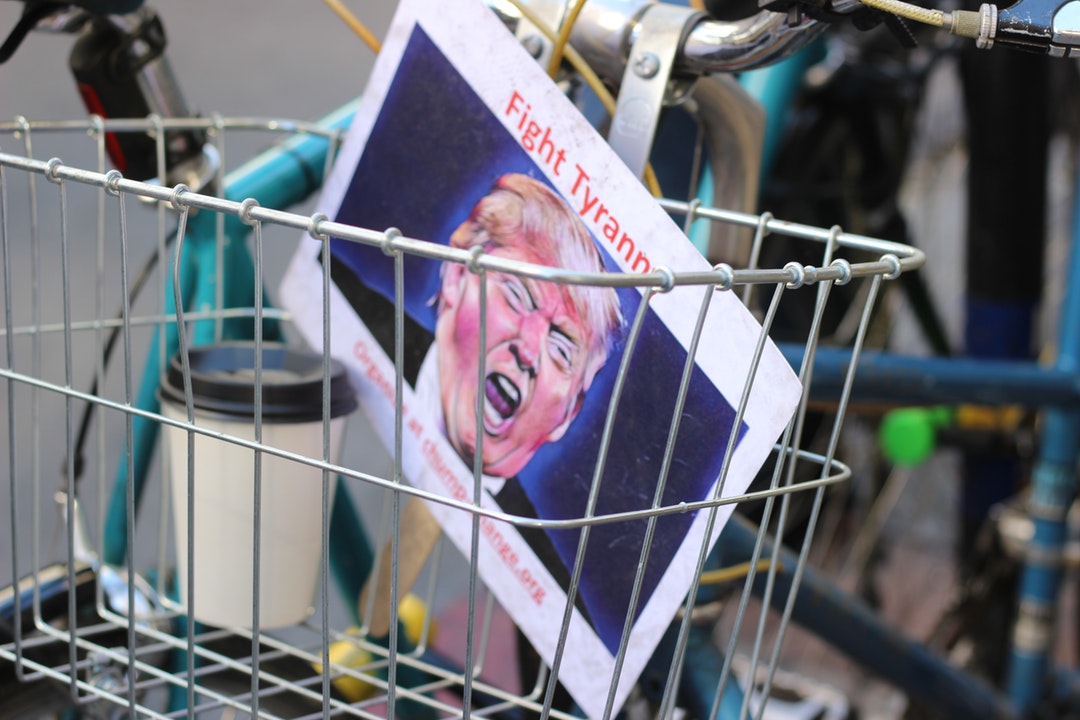 Fight Tyranny sign with Trump's face on it in the basket of a bicycle