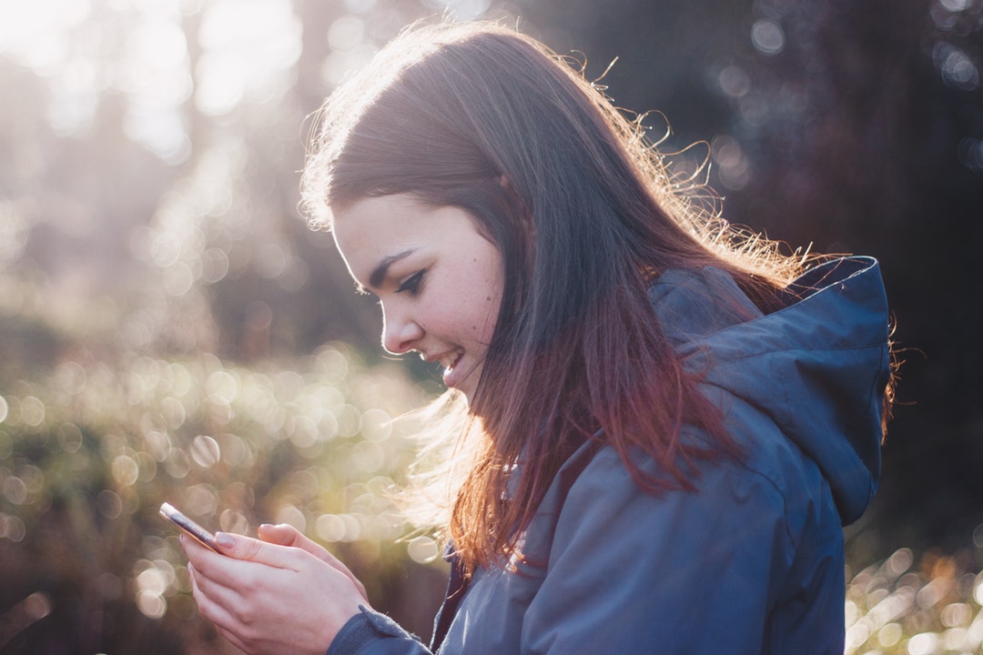 A young woman smiling while looking at a smartphone