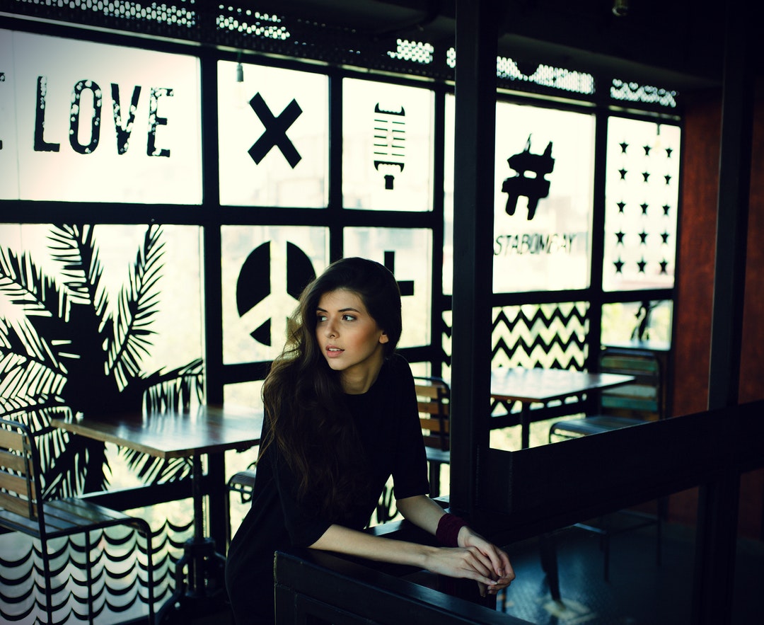 A young woman sits at a table in a cafe with decorated frosted windows