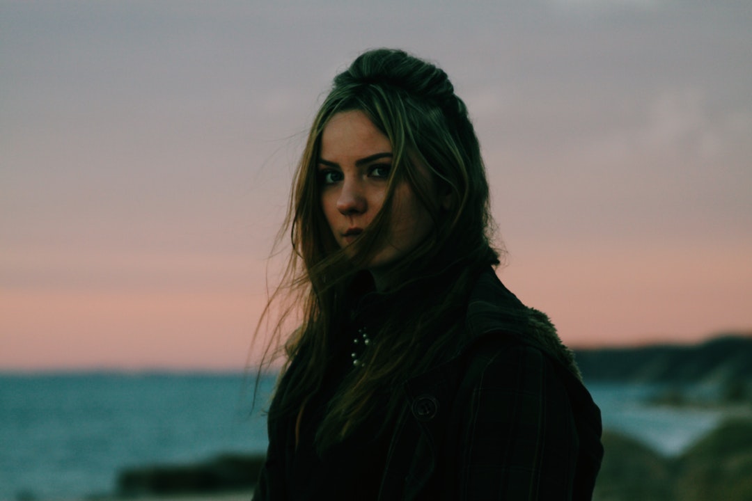 Woman with windblown hair looking serious at sunset