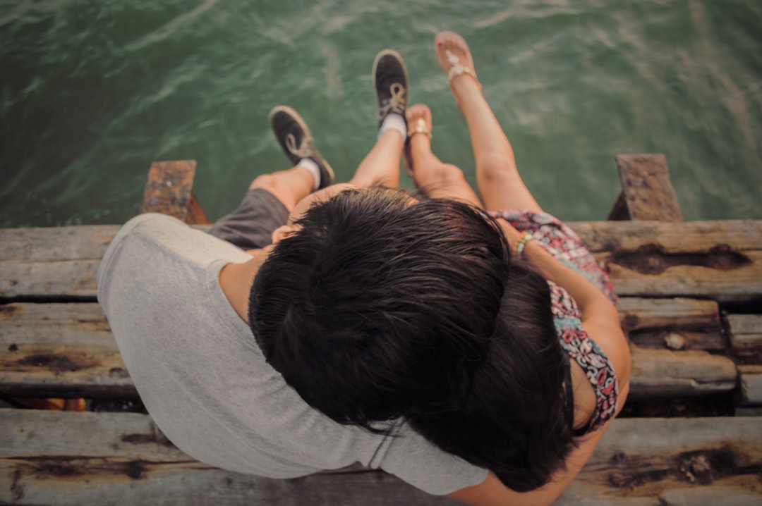Young woman and her boyfriend pictured sitting on a dock with their legs dangling
