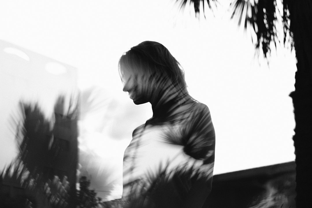 Silhouette of a woman in the reflection of glass with trees and plants around her