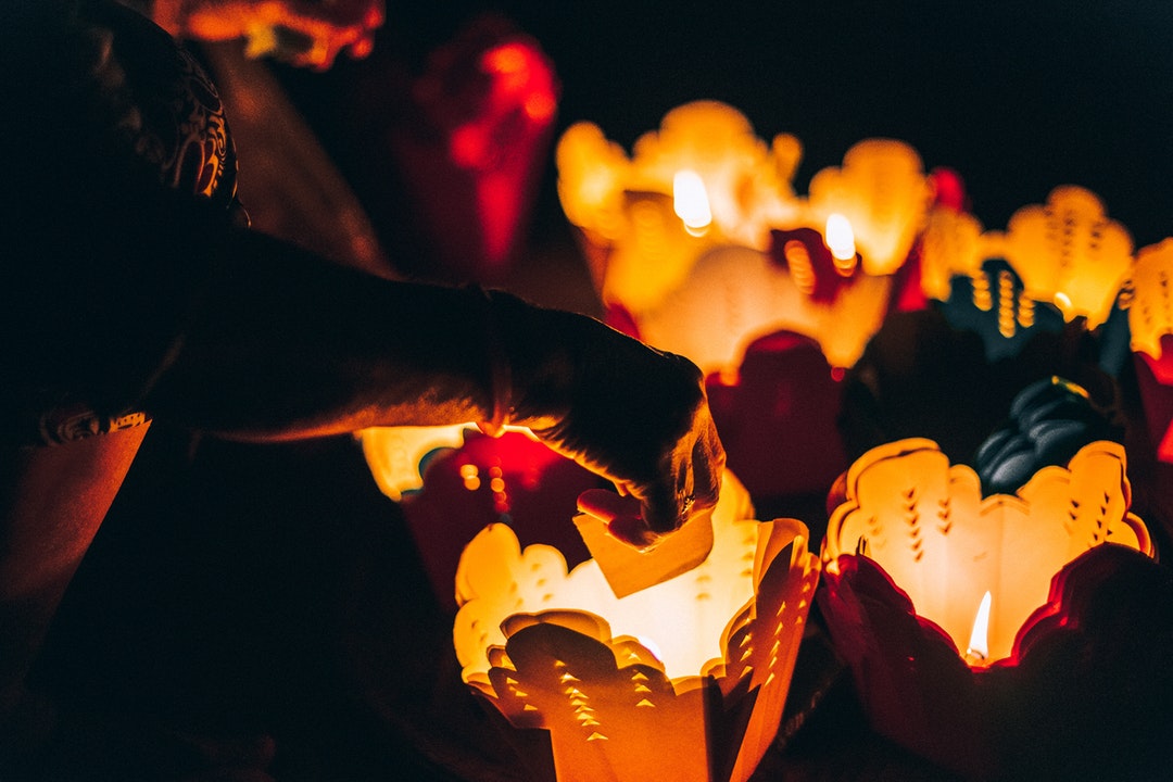 Person places candles inside paper takeout container lanterns
