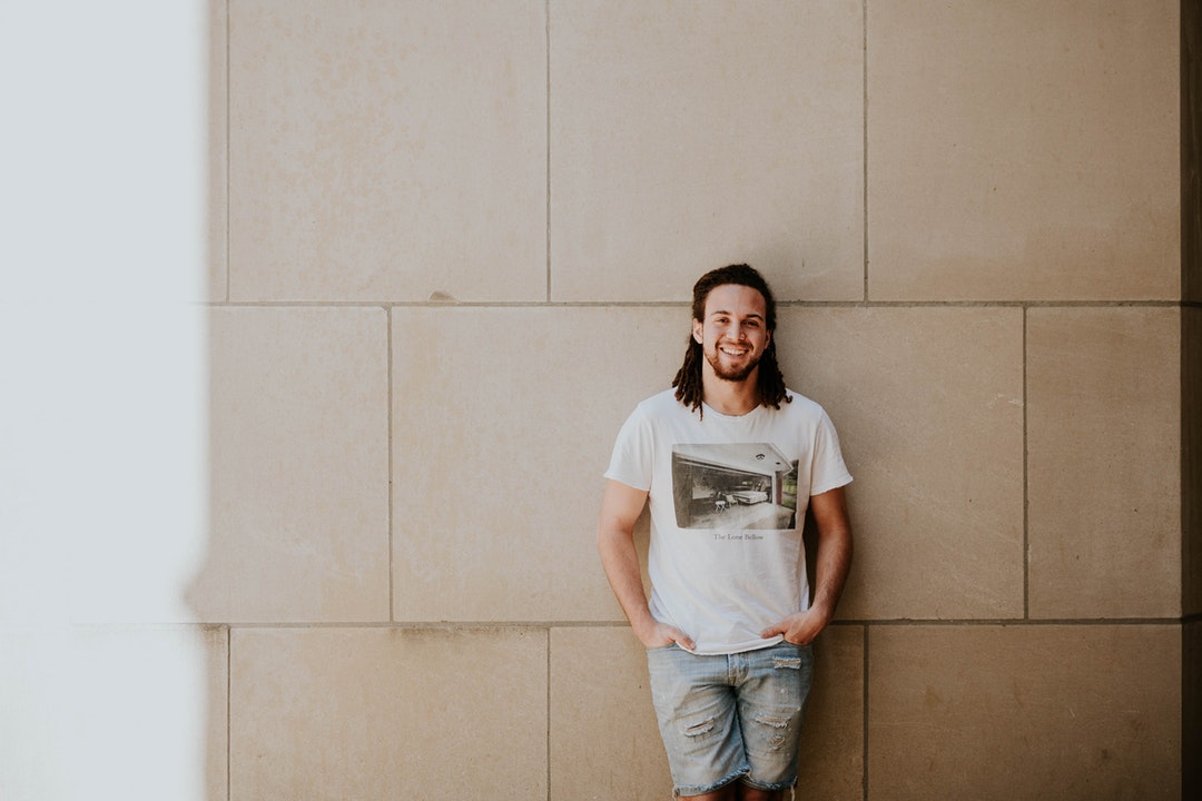A man wearing a t-shirt and denim cutoff shorts