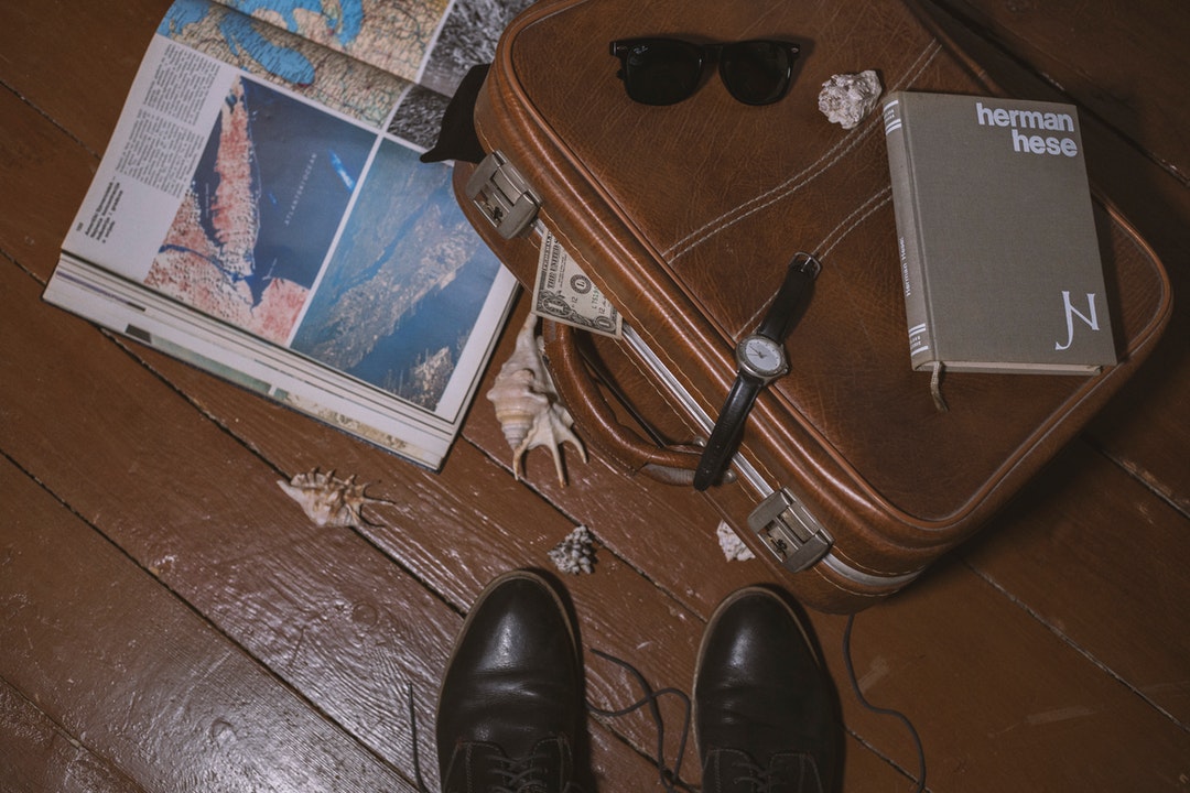 brown suitcase beside open book