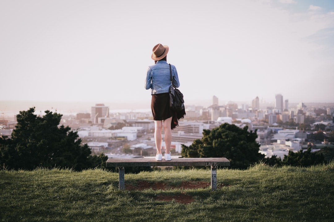 Woman standing on a park bench and surveying the city below