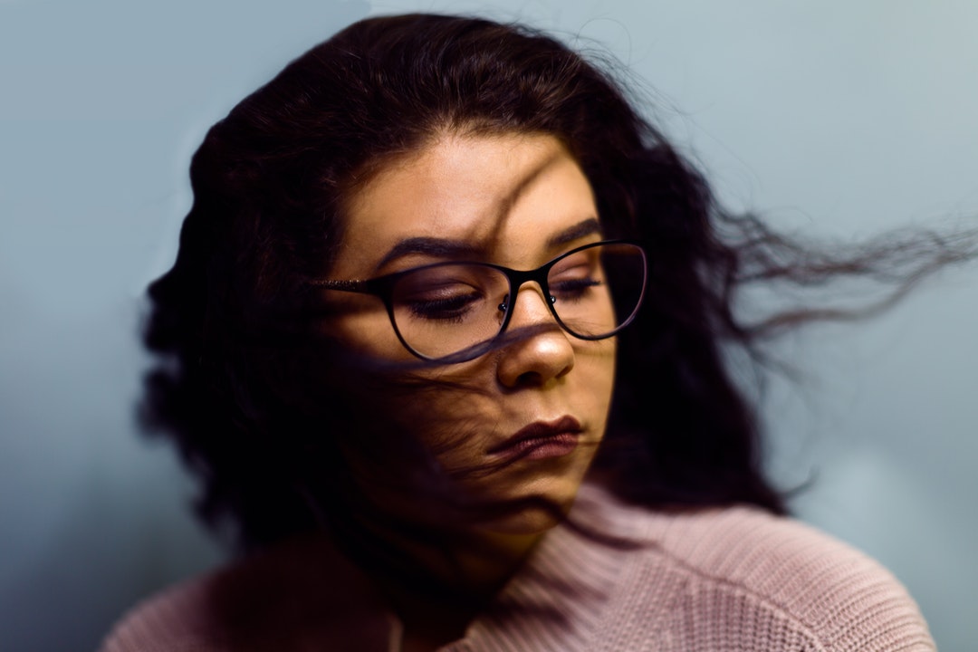 Serious woman in glasses shaking out curly hair