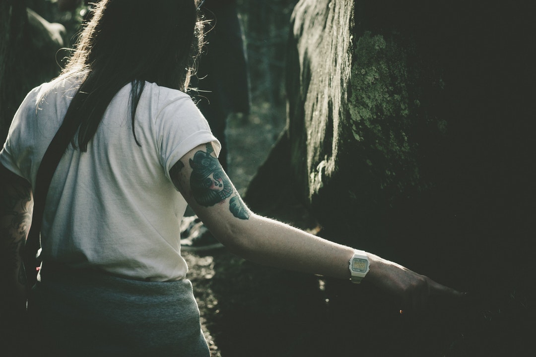 Woman with various tattoos on her arms walking through the forest of Dovbush Rocks