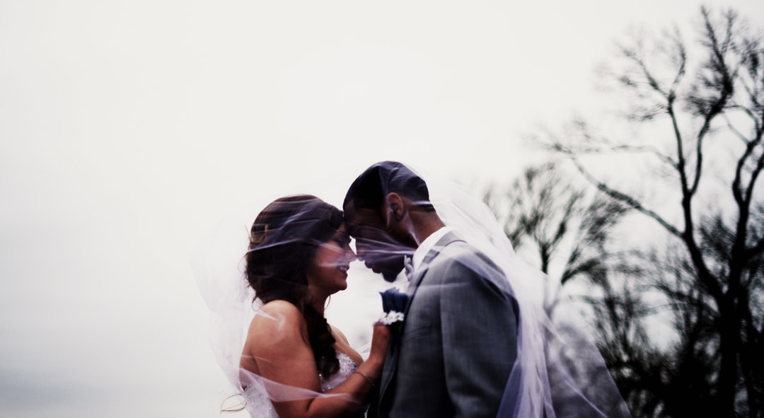 Bride and groom stand under the veil outside