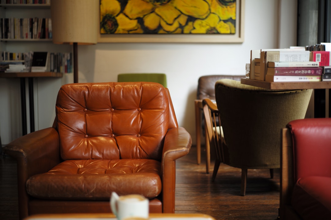 Interior of a sophisticated room with a stylish light brown leather arm chair with shelves filled with books
