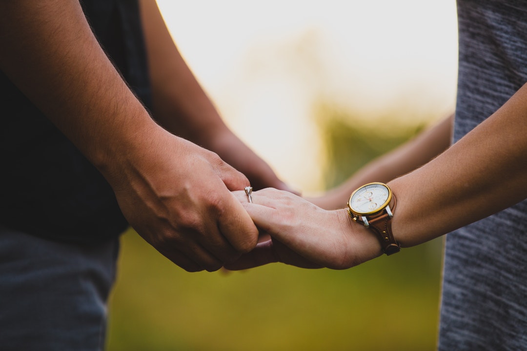 Close-up outdoors of man holding the hands of woman wearing a watch