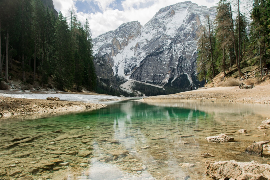 A shallow lake with a view on a tall snowy mountain peak