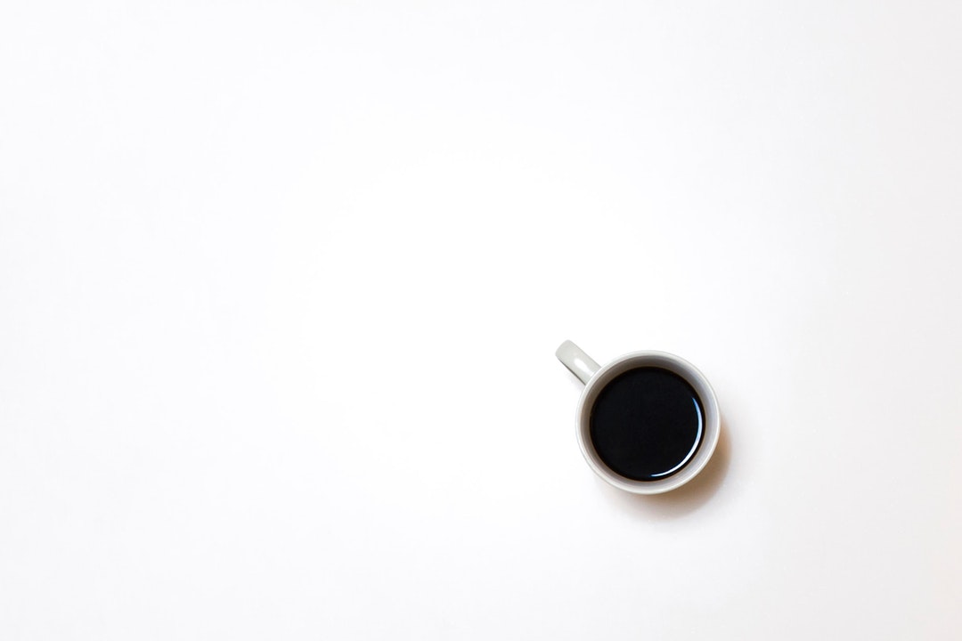 An overhead shot of a cup of coffee on a white surface