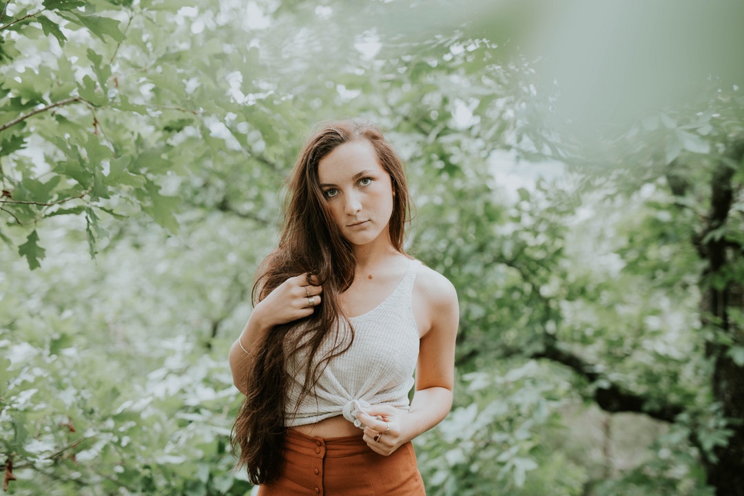 selective focus photography of woman in tank top standing in forest