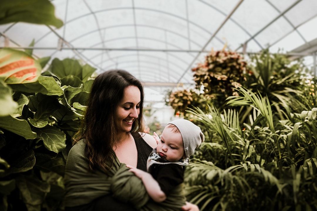 A mother holding her child in a greenhouse