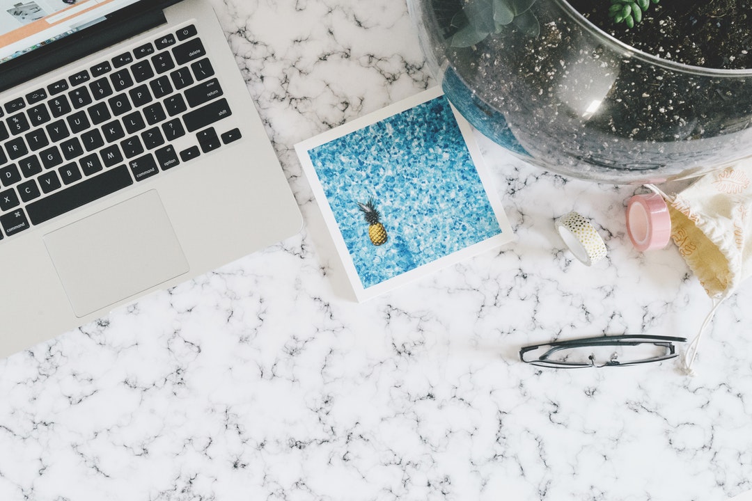 A Macbook and other items on top of a marble table.