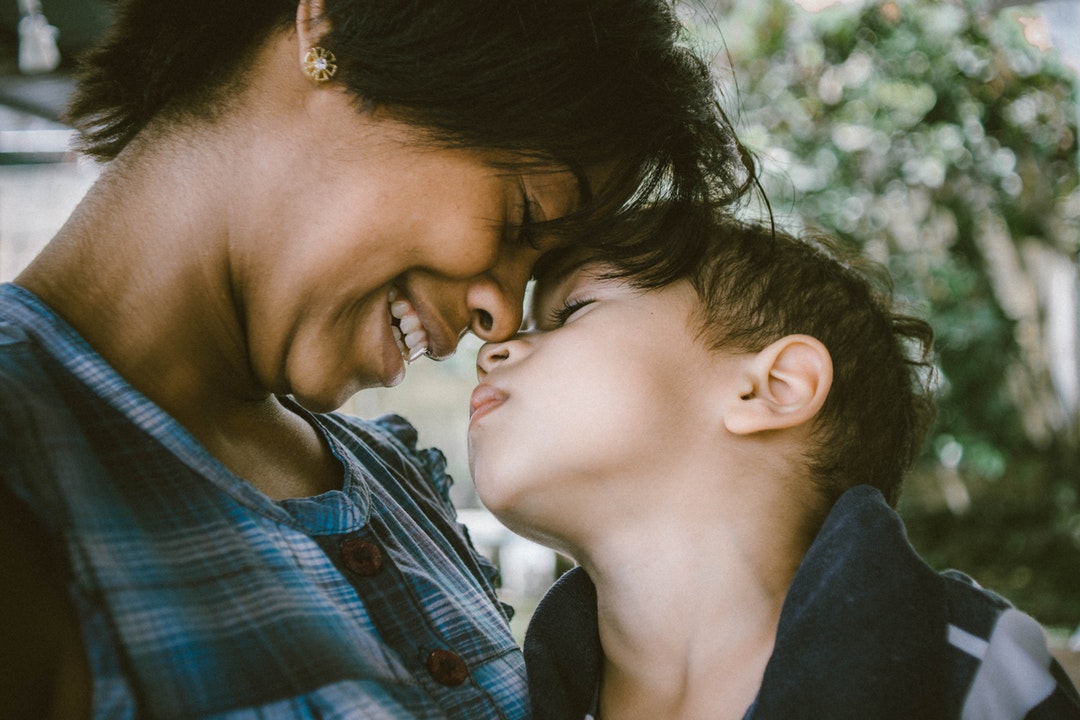 A woman smiles as she and her child touch their faces together in Juiz de Fora