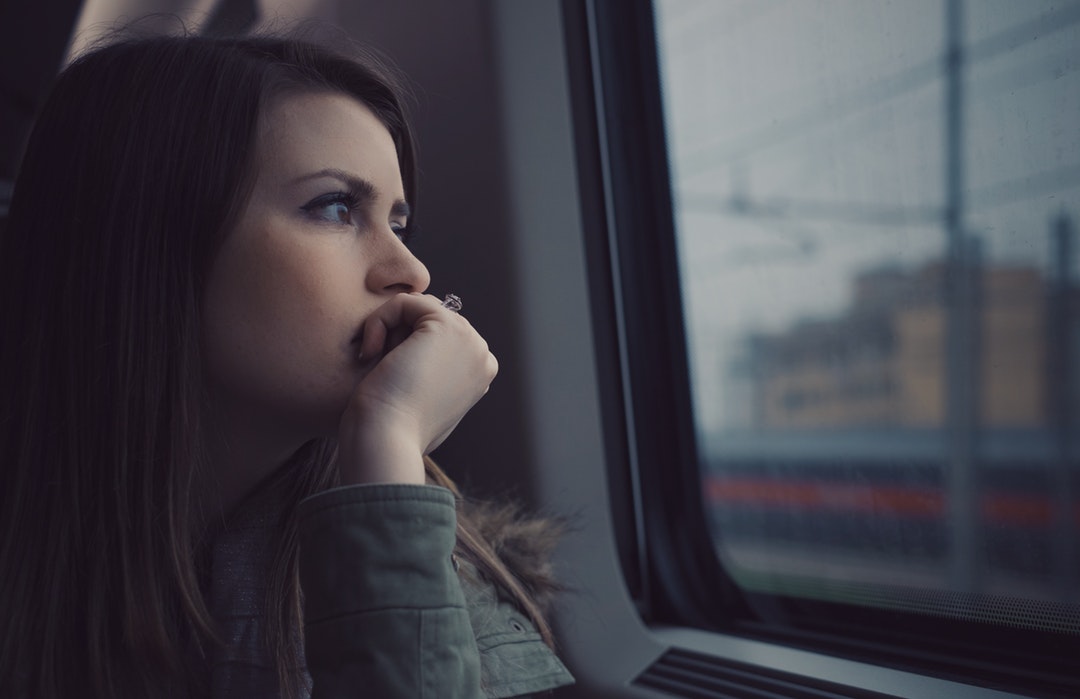 Thinking woman looking out a train car window alone