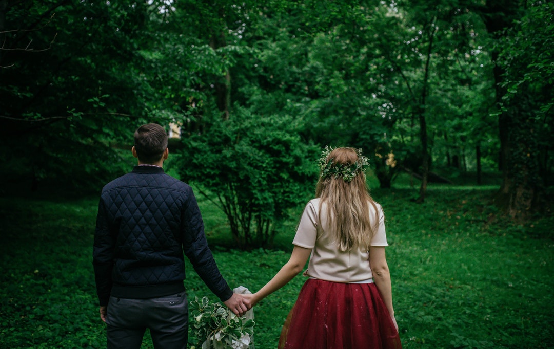 Couple wearing whimsical forest outfits holding hands