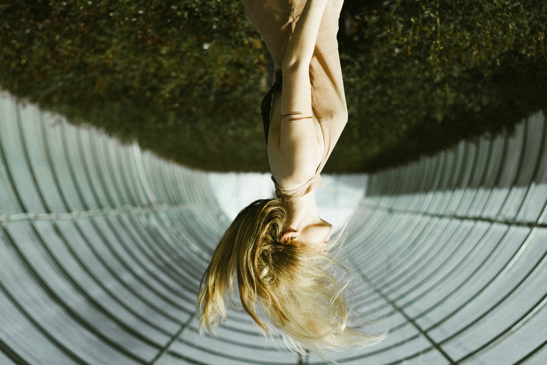 An upside down photograph of a blonde-haired woman in a greenhouse