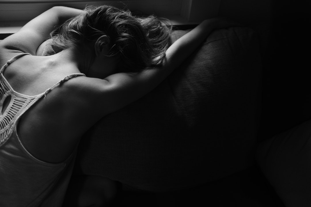 Black and white shot of woman lying face down on sofa cushion in Fayetteville