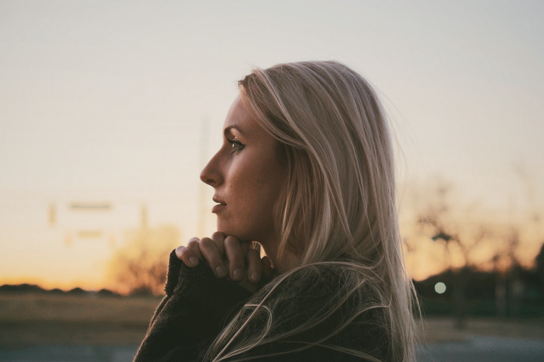 Side view of a woman thinking and praying with hands folded