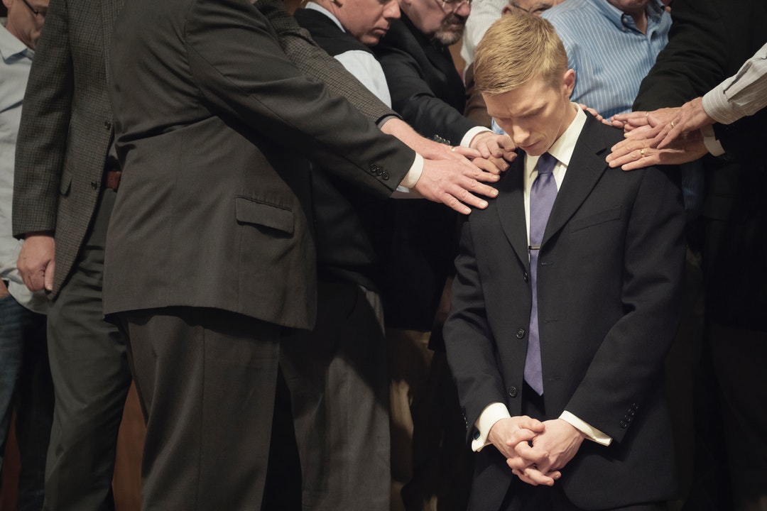 man bowing his head on another man
