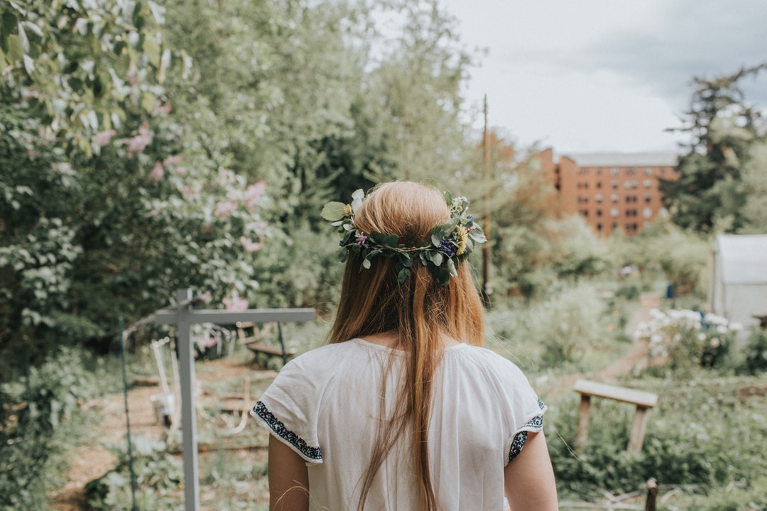 Back view of a woman wearing a floral crown in a garden in The Outback Farm.