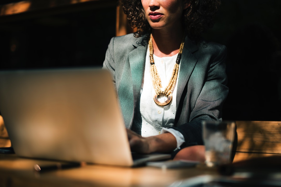 A businesswoman sitting at a table with a laptop and a glass of water