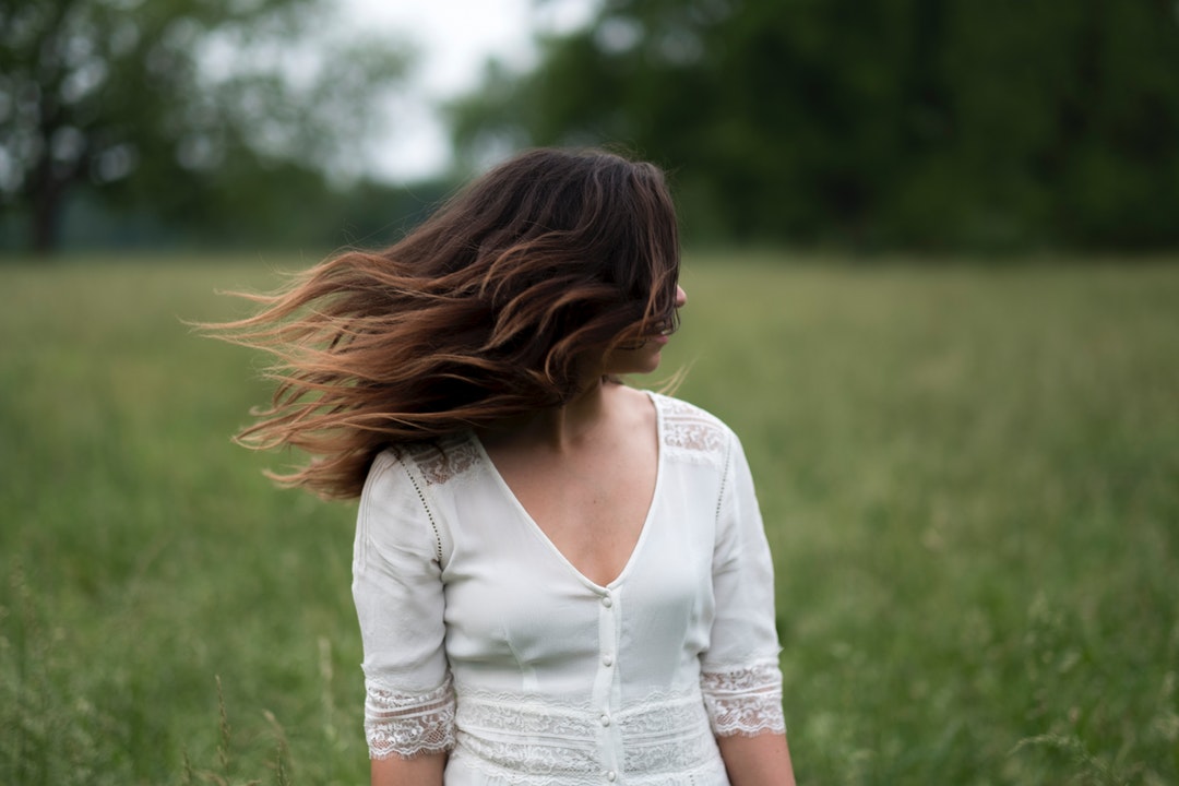 Woman in a white shirt with windblown hair in a field