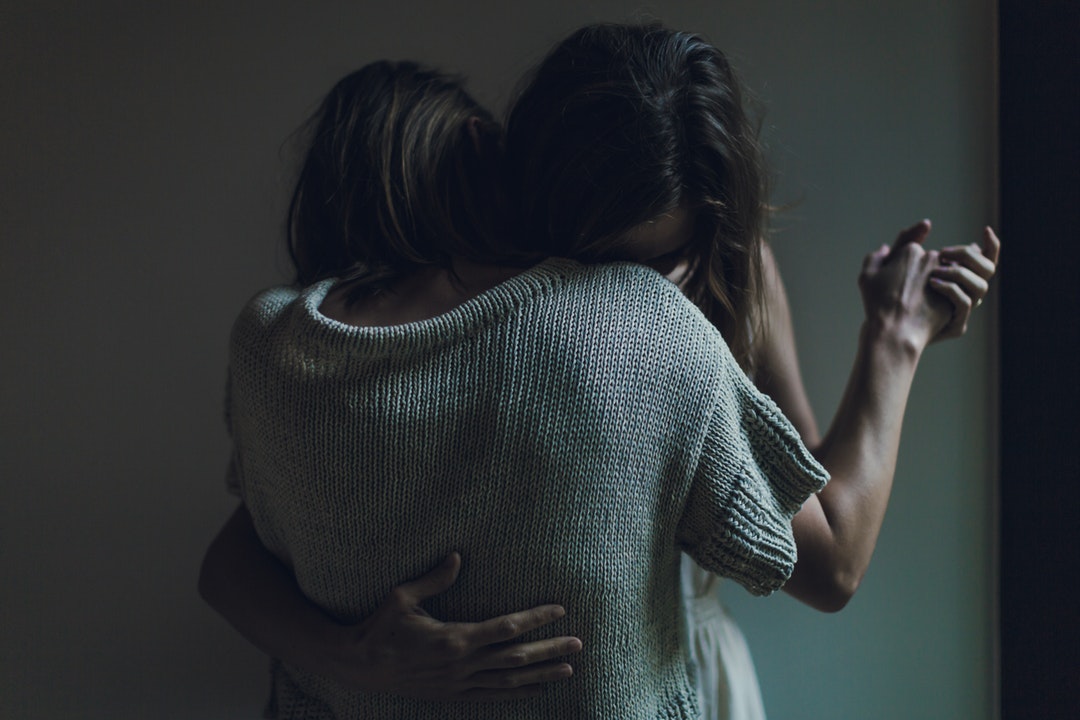 Two people holding each other close, dancing slowly in darkened room