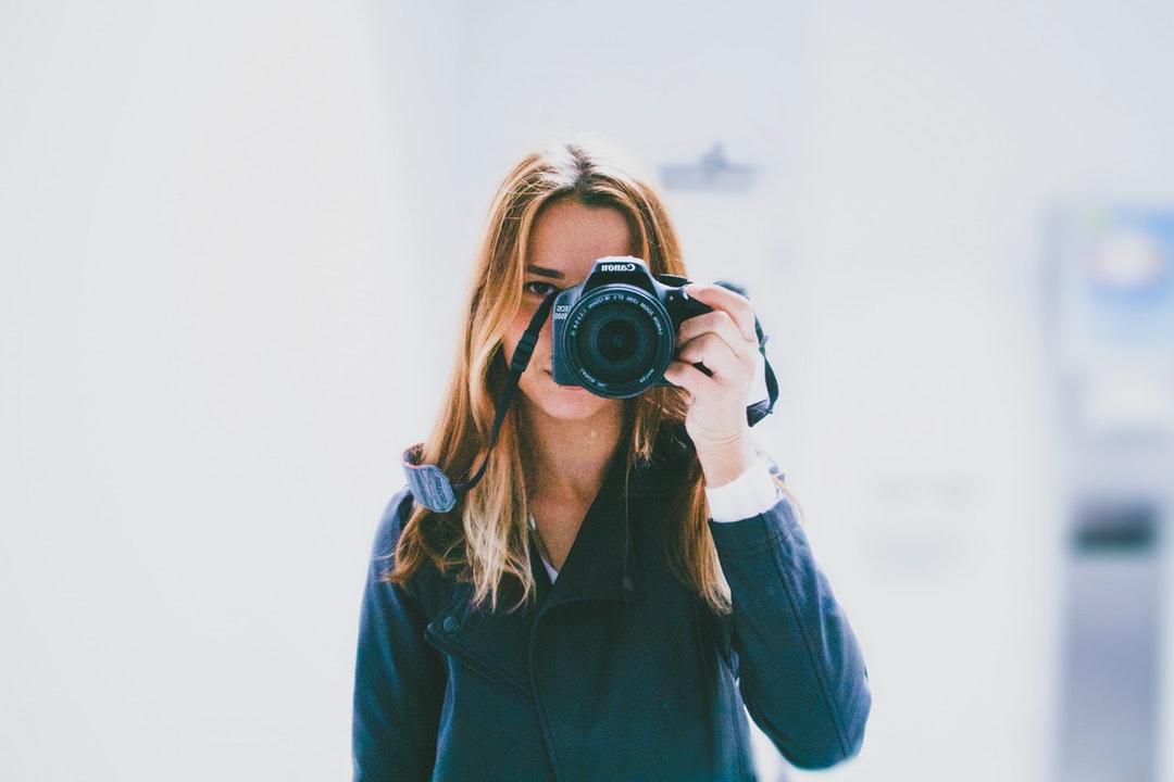 Photographer holding a camera over her face for a photo