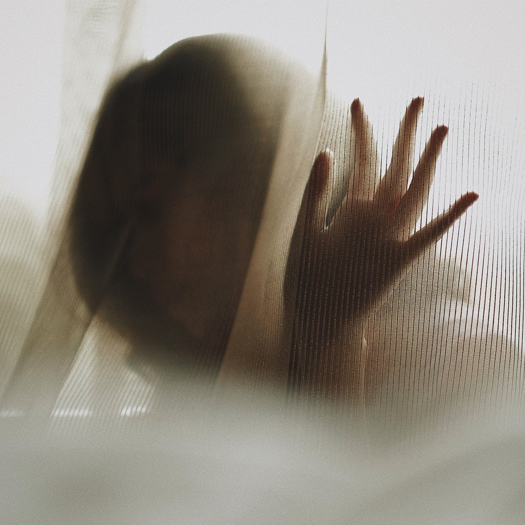 A silhouette of a woman behind a curtain