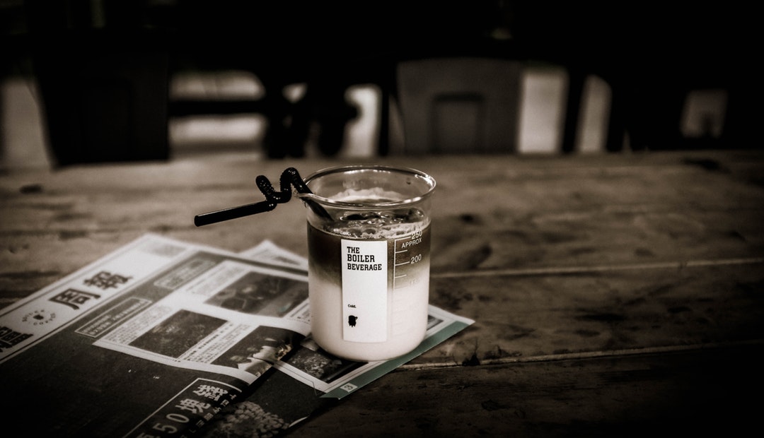 Coffee in a beaker with a straw on a newspaper