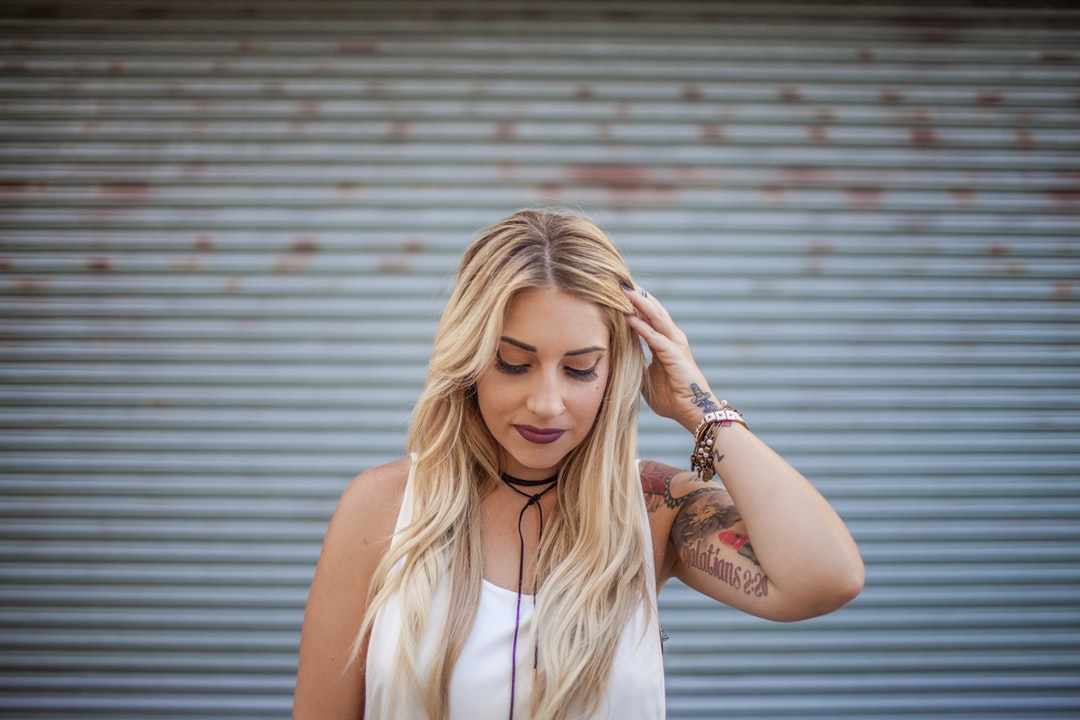 Happy woman with a tattoo fixes her hair and looks down