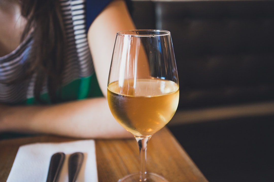 A macro view of a wine glass with white wine in it in Larrys