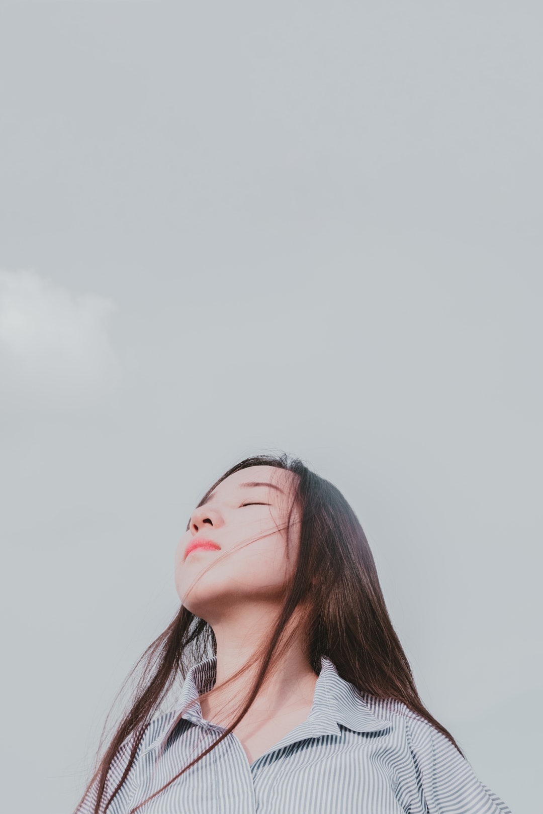 A woman closes her eyes and throws back her head toward the sky