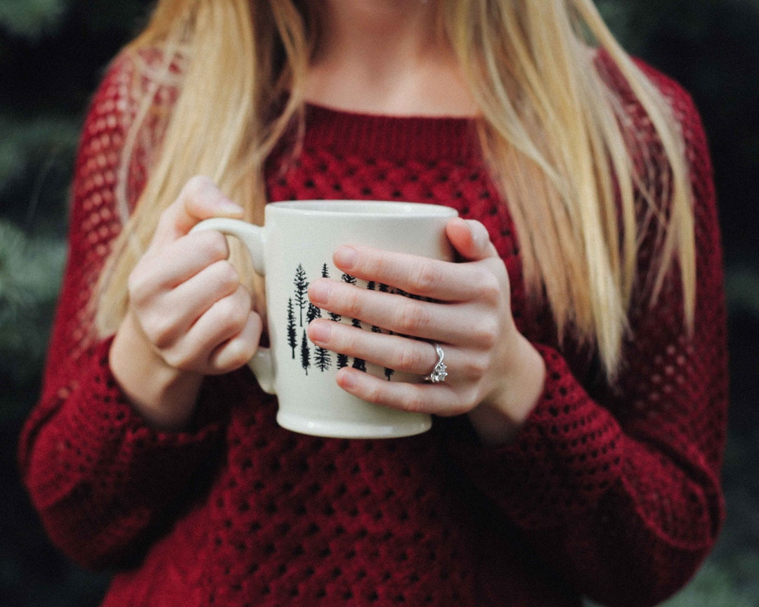 Woman wearing a red sweater holding a cozy mug of coffee